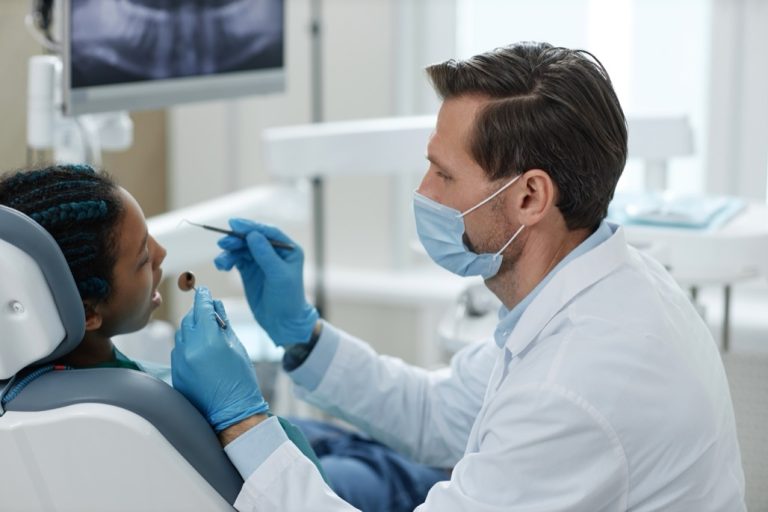Side,View,Portrait,Of,Male,Dentist,Wearing,Mask,While,Working